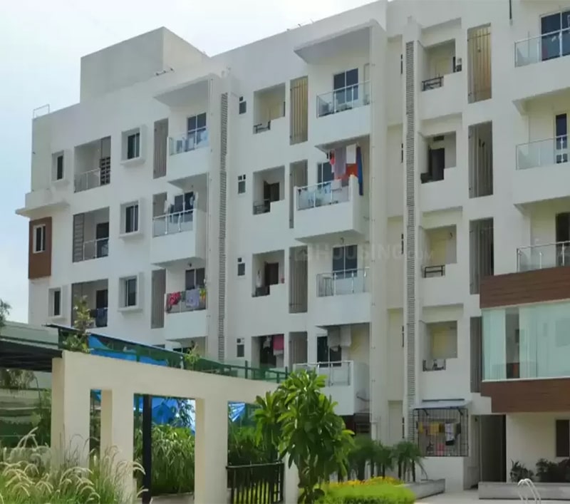 Exterior view of Mana Seldon, a new apartment project in Bangalore by top developers, showcasing a multi-story building with white facades, glass railings, and inviting common spaces for residents.